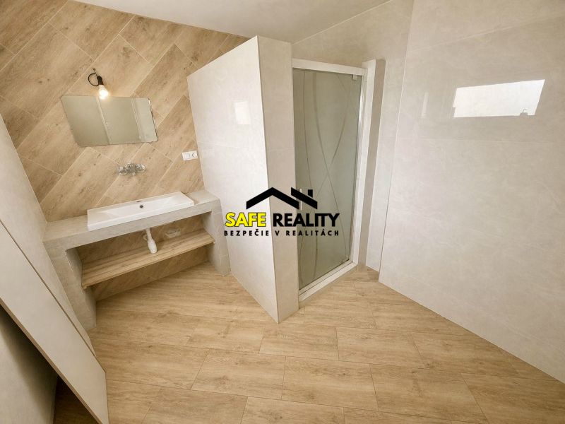 A bathroom in a family house with a wooden decor floor and a shower corner.