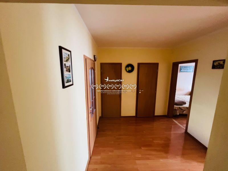 A hallway with a wooden decor floor in a 3-room apartment, several doors on the sides.