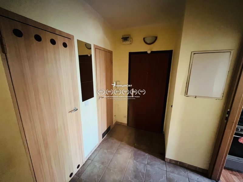 A hallway in a 3-room apartment with tiles and wooden doors.