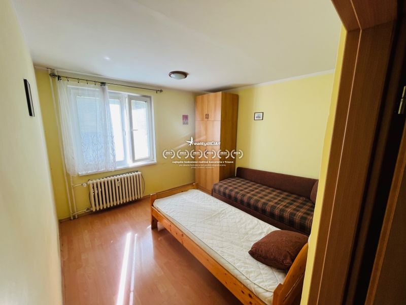 A room in a 3-room apartment with a bed, a sofa, and a floor with a wooden decor.