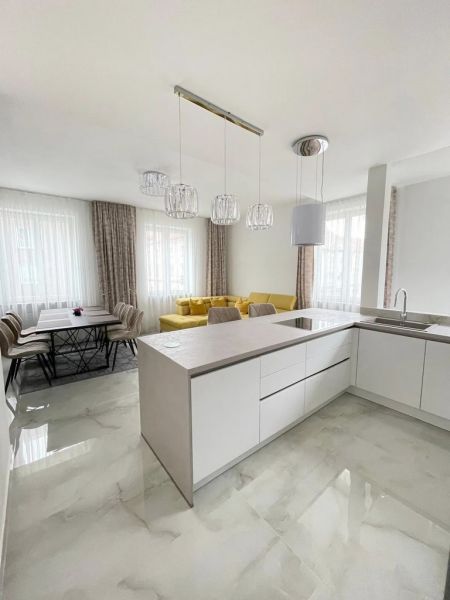 A kitchen in a 3-room apartment with a yellow sofa and a dining table.