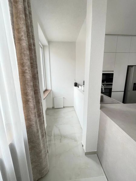 A kitchen in a 3-room apartment with white cabinets and a marble floor.
