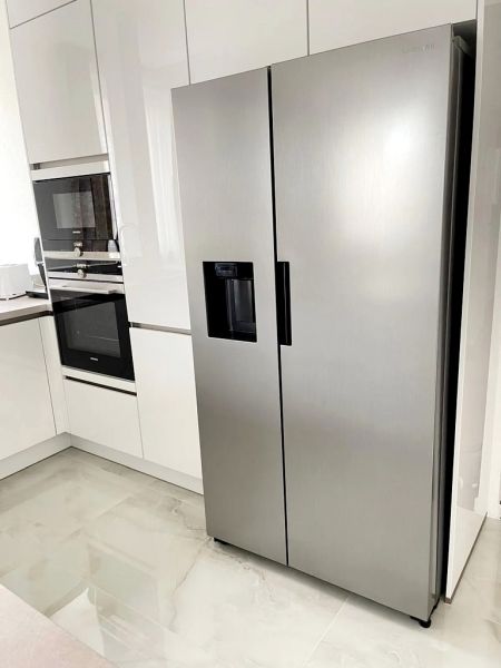 A kitchen in a 3-room apartment with a stainless steel refrigerator and ceramic tiles.