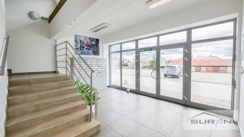 An office interior with a staircase, mailboxes, and large glass doors.