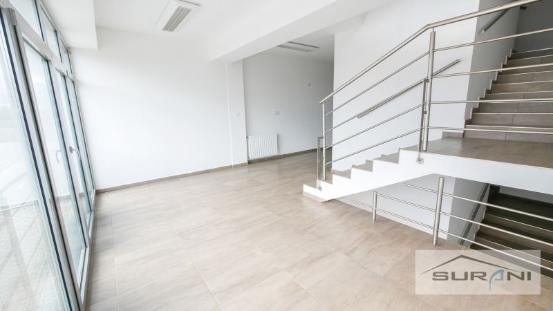 Offices with a staircase, glass wall, and wood-patterned flooring.