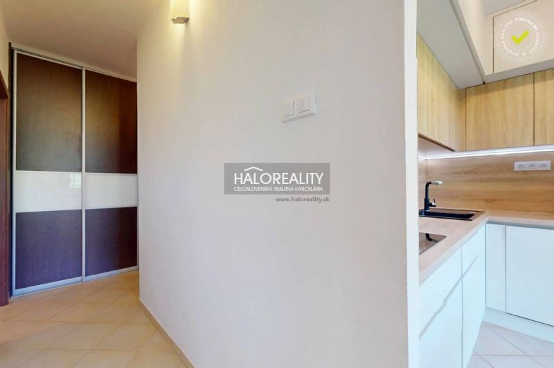 A hallway with ceramic tiles, a built-in wardrobe, and a kitchen with wooden decor in a 3-room apartment.