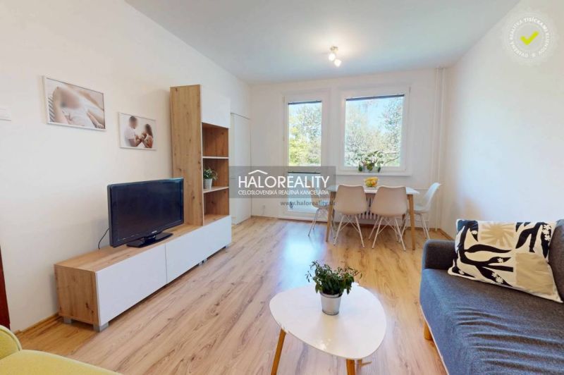 Living room in a 3-room apartment with a wooden decor floor, a television, and a dining table.