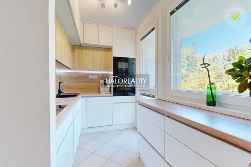 Kitchen in a 3-room apartment with white cabinets and wood decor.