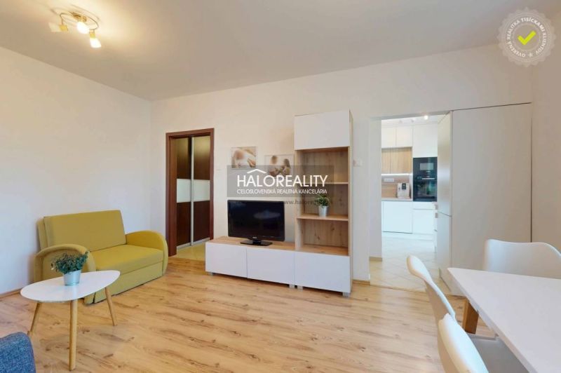 Living room in a 3-room apartment with a wooden decor floor, minimalist furniture, and a television.