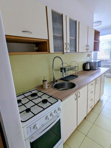 A kitchen in a 2-room apartment with a stove, sink, and kitchen cabinets.