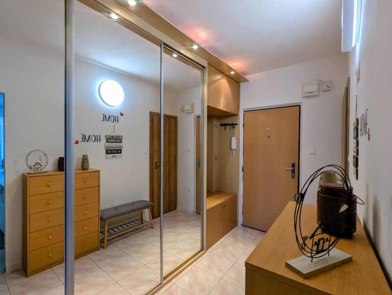 Hallway of a 2-room apartment with a large wardrobe, entrance door, and decorations.