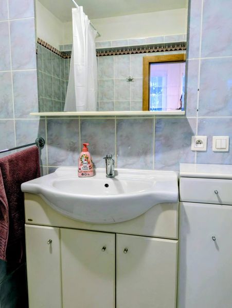 A bathroom in a 2-room apartment with a sink, mirror, and blue tiles.