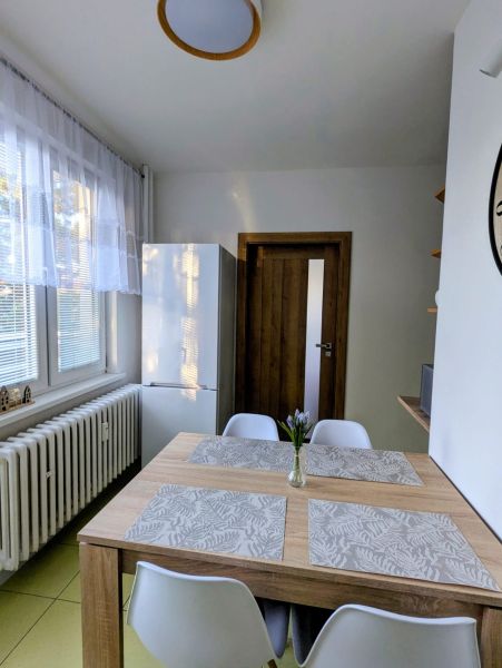 Dining area in a 2-room apartment with a wooden table and white chairs.