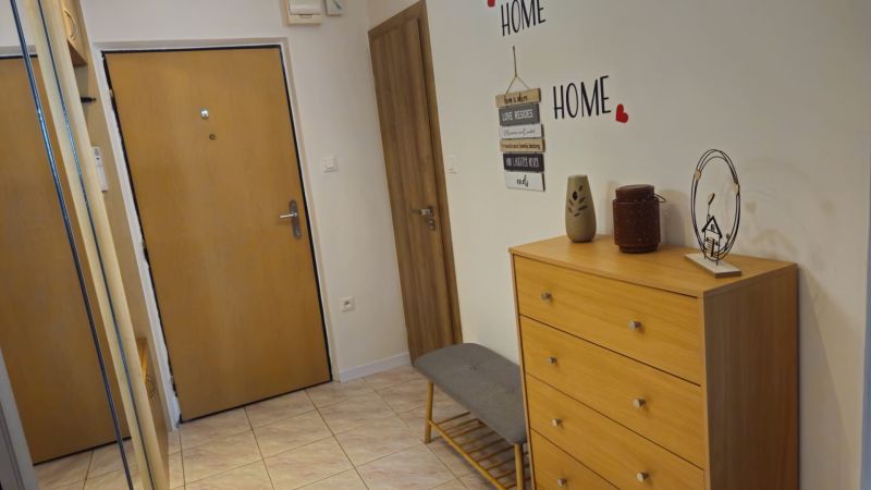 A hallway in a 2-room apartment with a dresser, a mirror, and decorations on the wall.