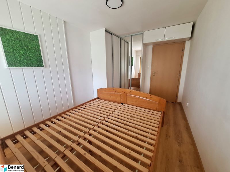 Bedroom in a 2-room apartment with a wooden bed, built-in wardrobe, and wall decoration.