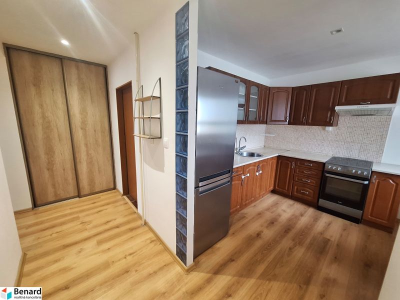 A kitchen in a 2-room apartment with wooden furniture and a built-in wardrobe.