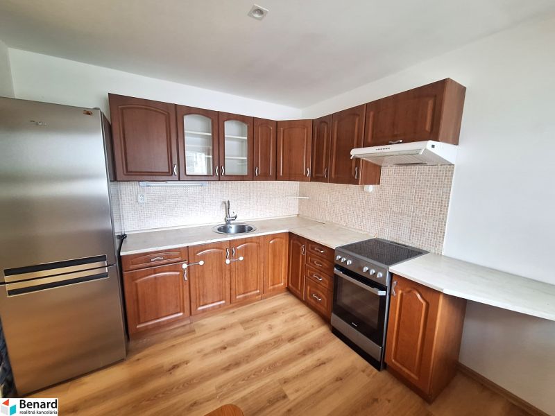 A kitchen in a 2-room apartment with wooden cabinets and kitchen appliances.
