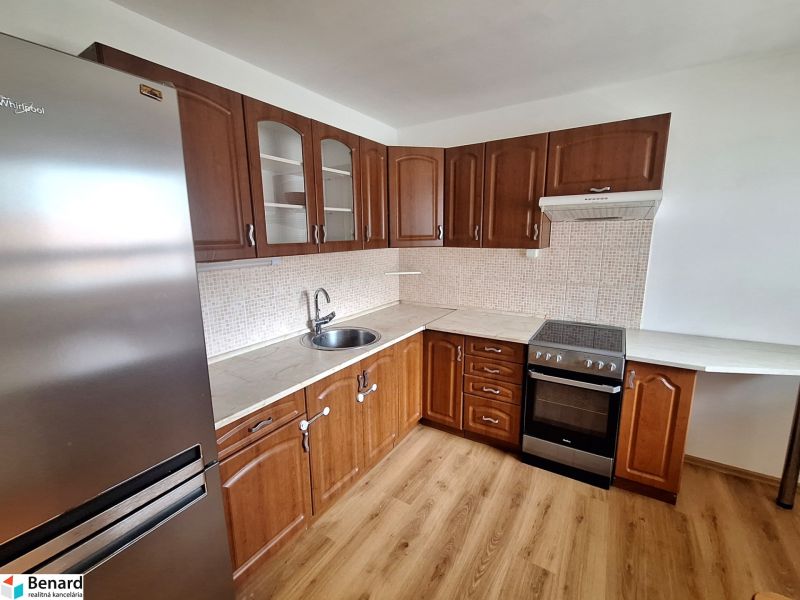 A kitchen with built-in appliances and a wooden decor floor in a 2-room apartment.