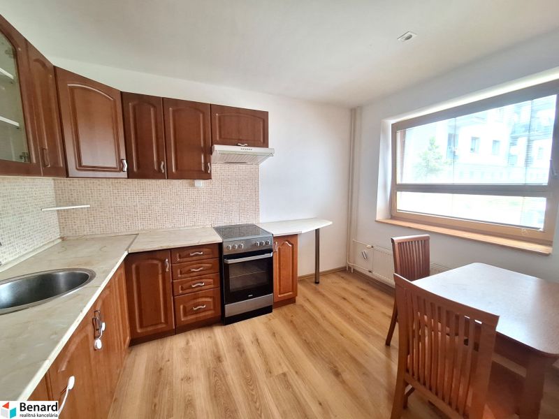 A kitchen in a 2-room apartment with built-in cabinets and a dining table.