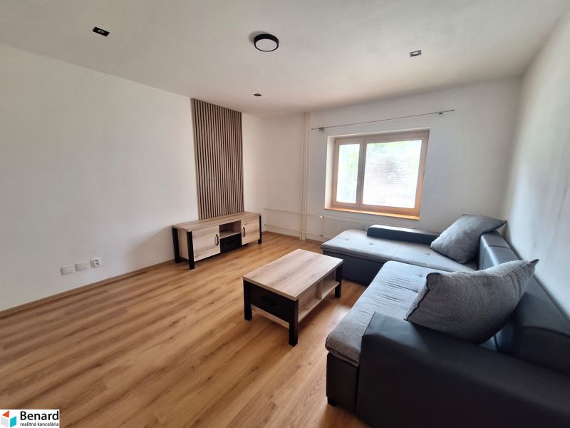 Living room with a corner sofa and wooden furniture in a 2-room apartment.