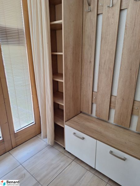 A wooden hanger with storage space by the window in a 2-room apartment.