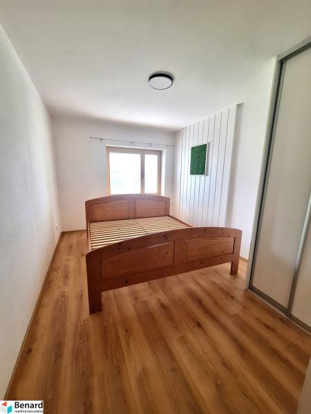 A bedroom with a wooden bed and a built-in wardrobe in a 2-room apartment.