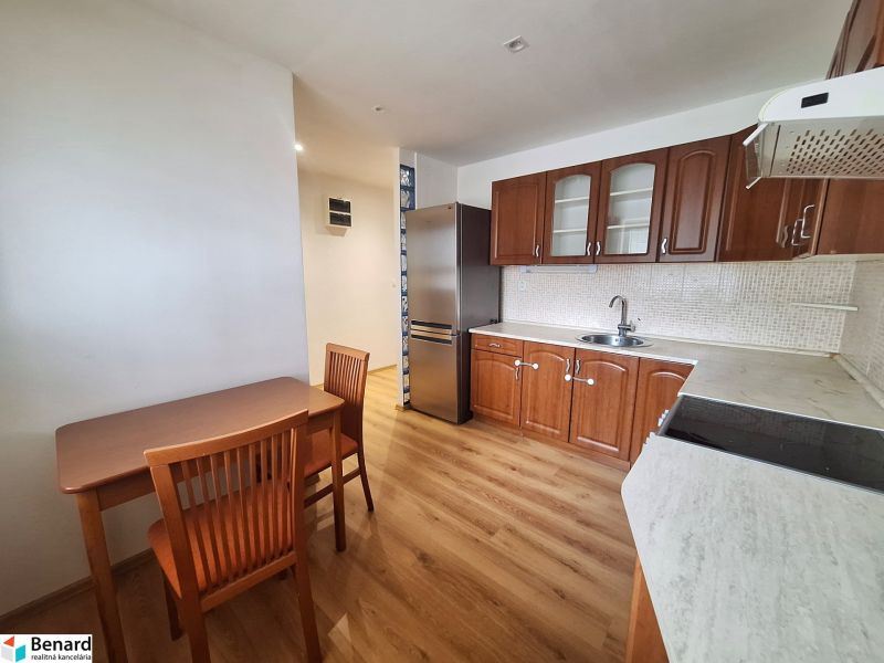 A kitchen with wooden furniture and appliances in a 2-room apartment.