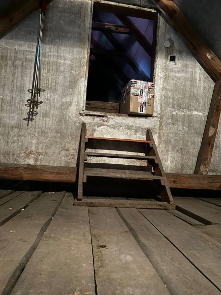 The attic of the family house with wooden stairs and a package.