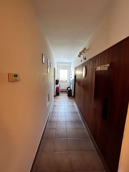 A hallway in a family house with tiles and wooden wall paneling.