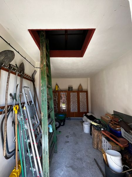 A storage space with tools in a family house, with access to the attic via a ladder.