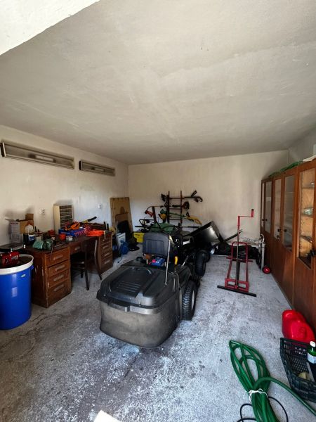 A garage in a family house with various tools and a ride-on lawnmower.