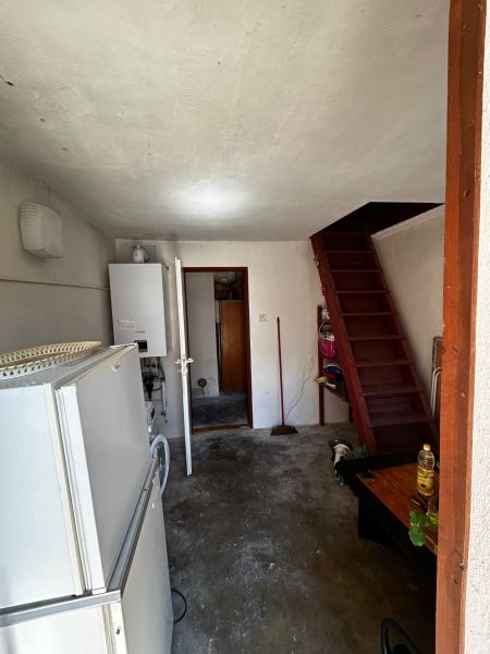 Interior of a family house with a refrigerator, boiler, and wooden stairs.
