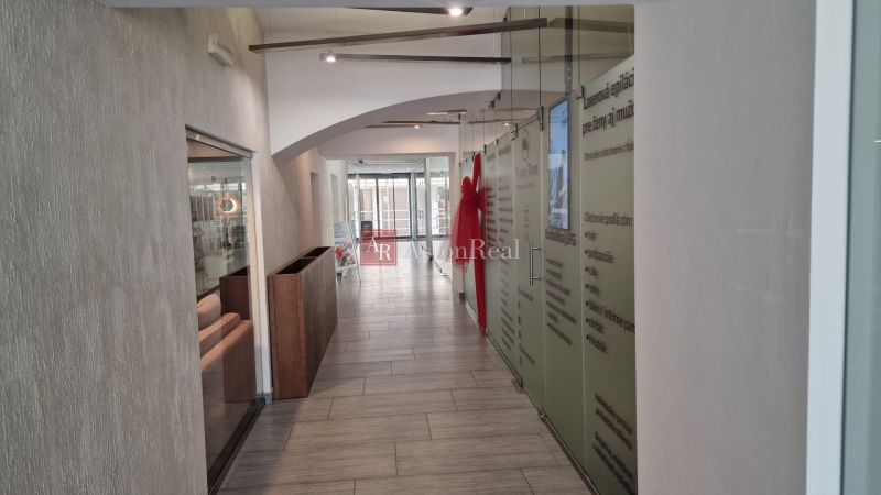 Interior of commercial premises with a long corridor space, glass walls, and a light floor.
