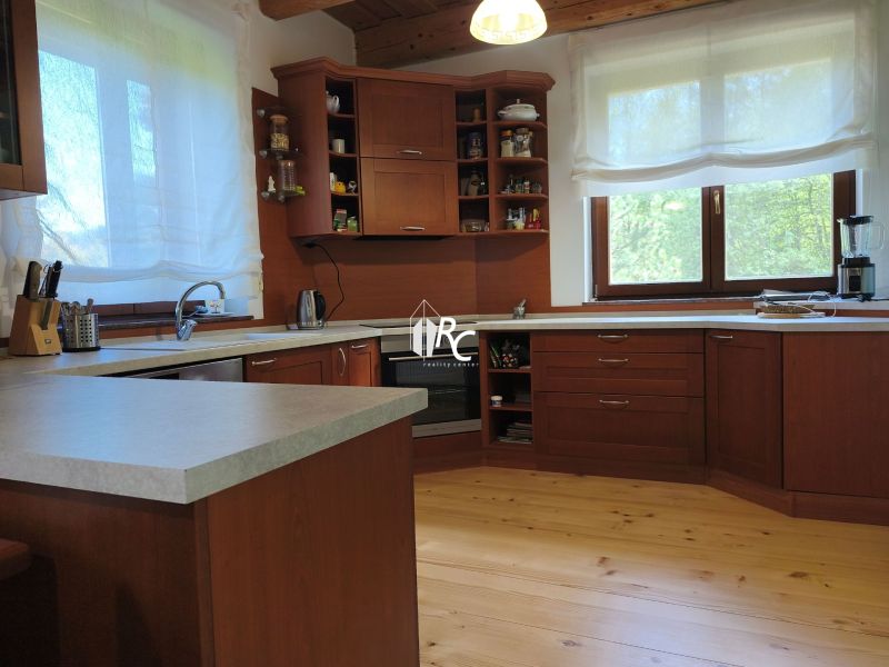 A kitchen in a family house with dark wood cabinets and a wood-patterned floor.