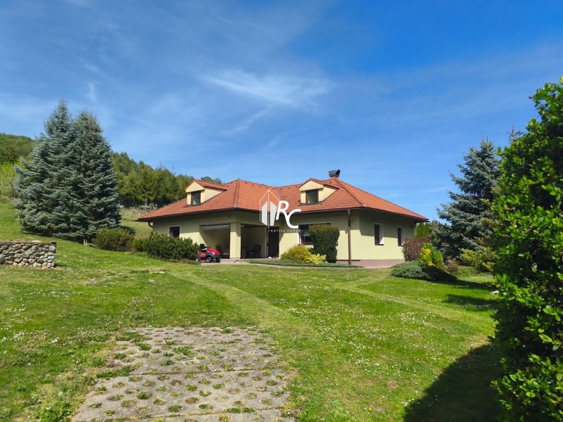 A family house in Trebostovo with a red roof, surrounded by a green lawn and trees.