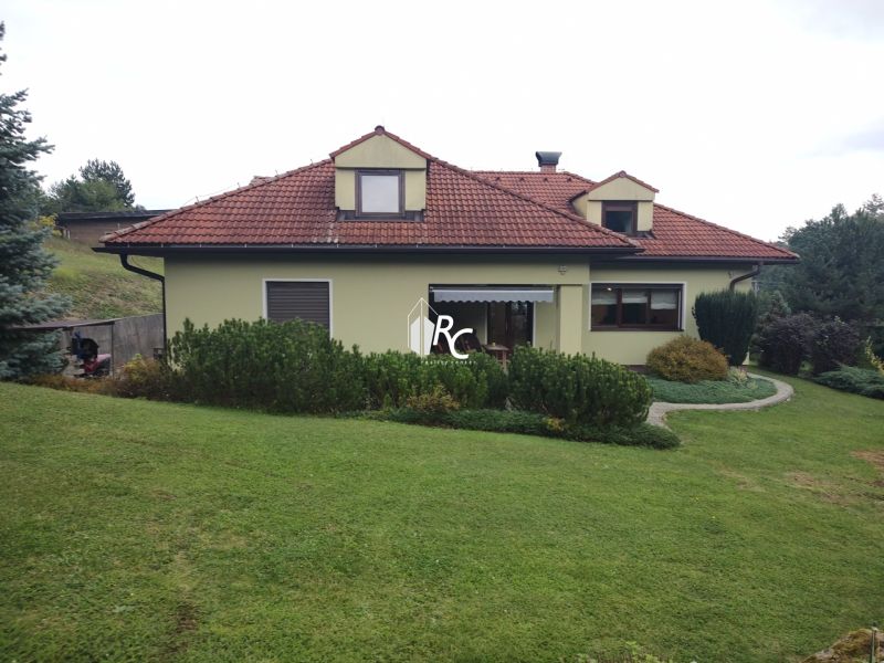 A family house in Trebostovo with a red roof surrounded by green lawn and shrubs.