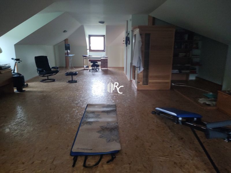 Attic room in a family house with a wooden decor floor and exercise equipment.