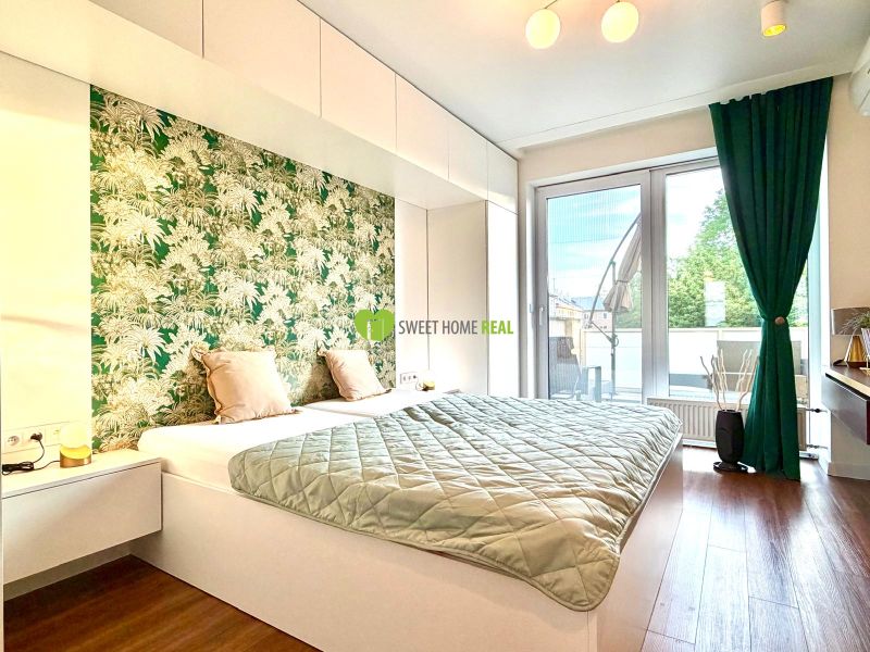 A bedroom in a three-room apartment with a wooden decor floor and a green curtain.
