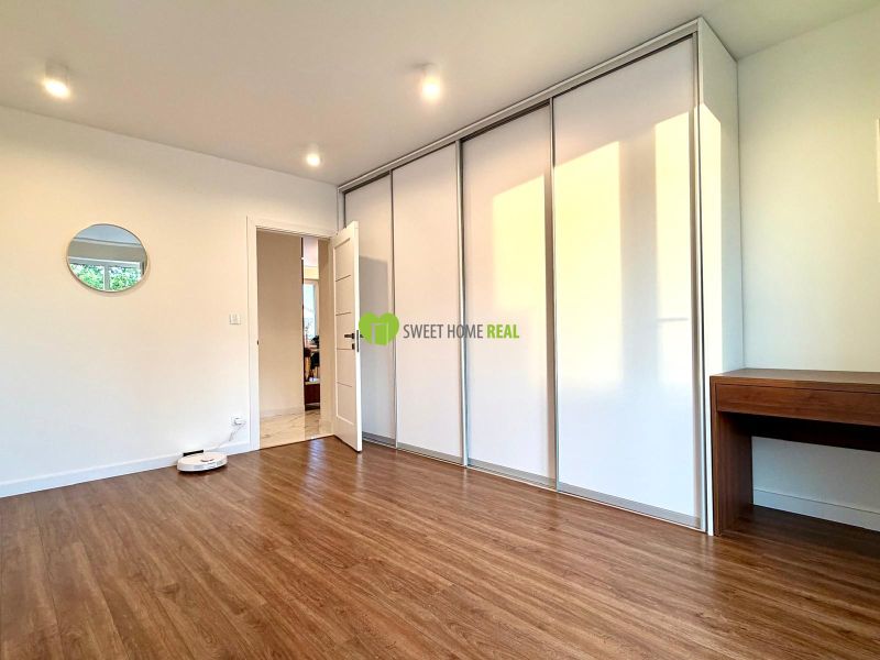 A room in a 3-room apartment with a wooden decor floor, a built-in wardrobe, and a mirror.