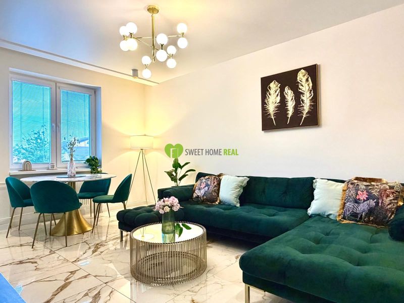 Living room in a 3-room apartment with a striking green sofa and marble flooring.