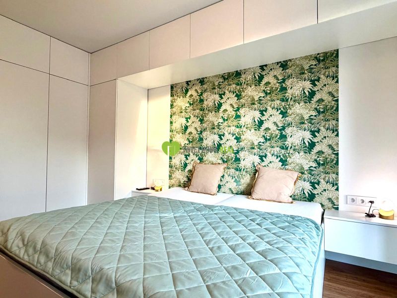 Bedroom in a 3-room apartment with a wooden decor floor and green wallpaper.