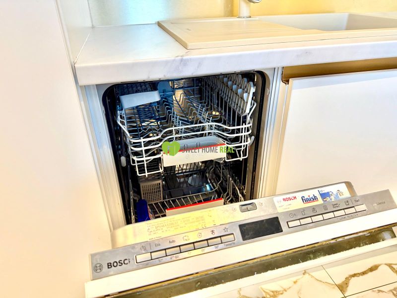 Dishwasher in the kitchen of a 3-room apartment, open door showing the interior.