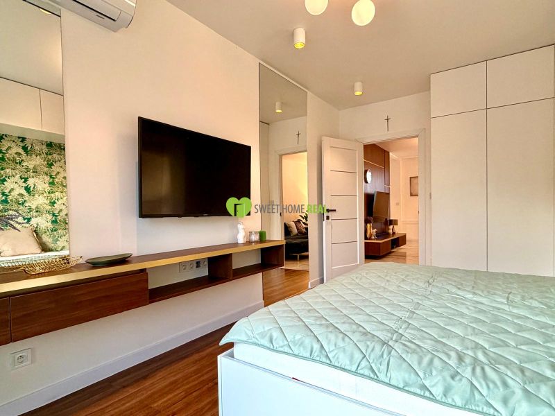 Bedroom in a 3-room apartment with a television and a floor with a wood decor.