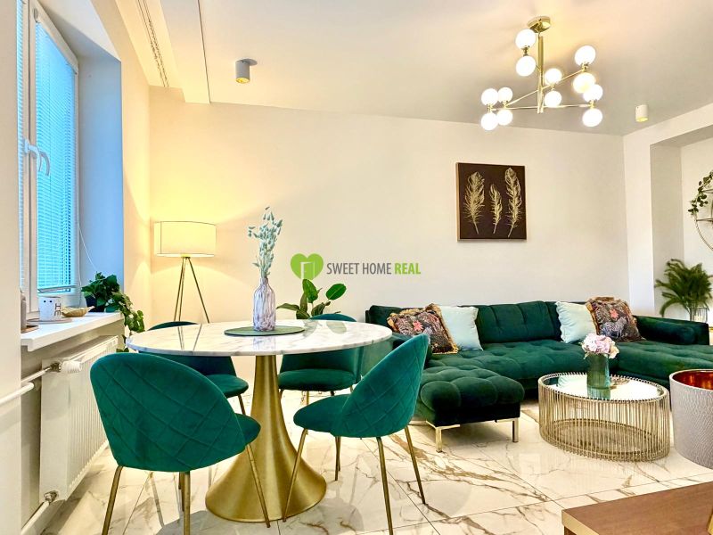 Living room in a 3-room apartment, green sofa, marble table, striking light fixture.