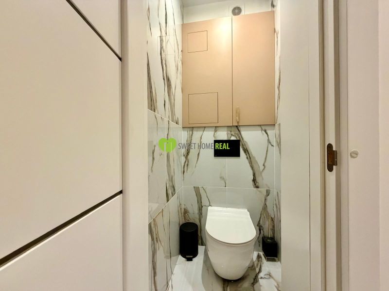 Bathroom in a 3-room apartment with marble-patterned tiles and a wall-mounted toilet.