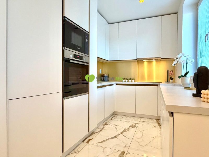 White kitchen in a 3-room apartment with marble flooring and built-in appliances.