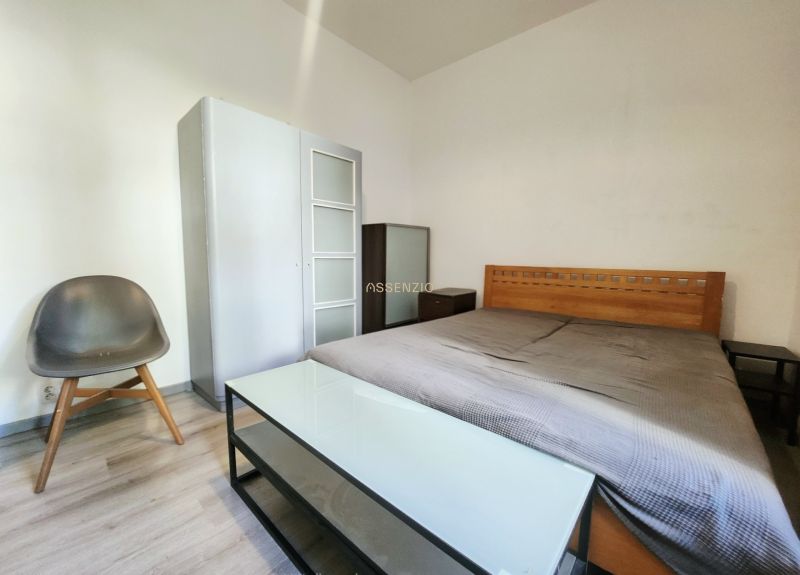 Bedroom in a 2-room apartment with a wooden bed, wardrobe, and chair.