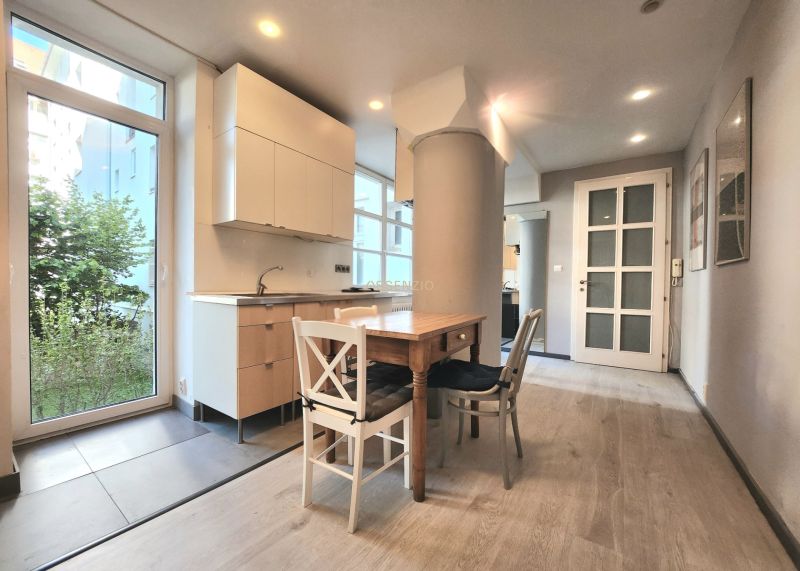 A kitchen in a 2-room apartment with a wooden table and a floor with a wooden decor.