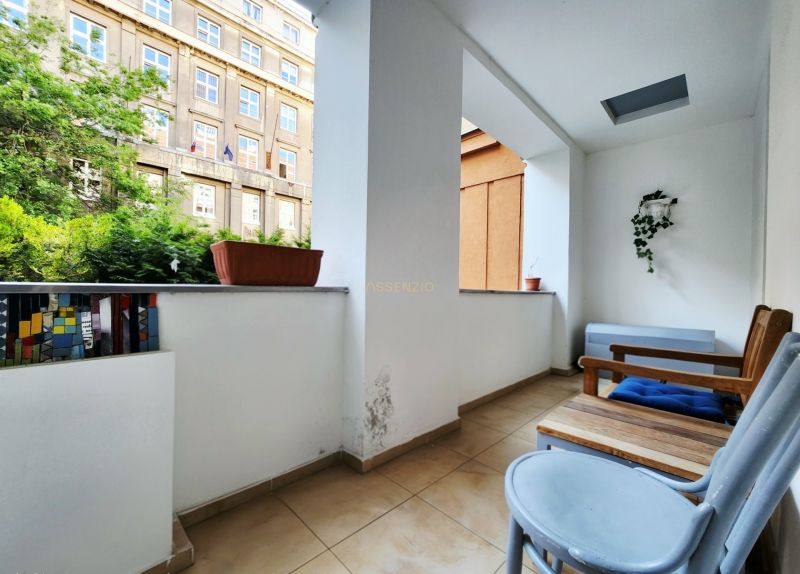A balcony in a 2-room apartment with flower pots and wooden furniture.