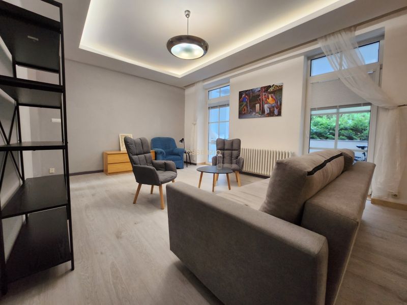Living room with a gray sofa, wood-patterned floor, and armchairs in a two-room apartment.